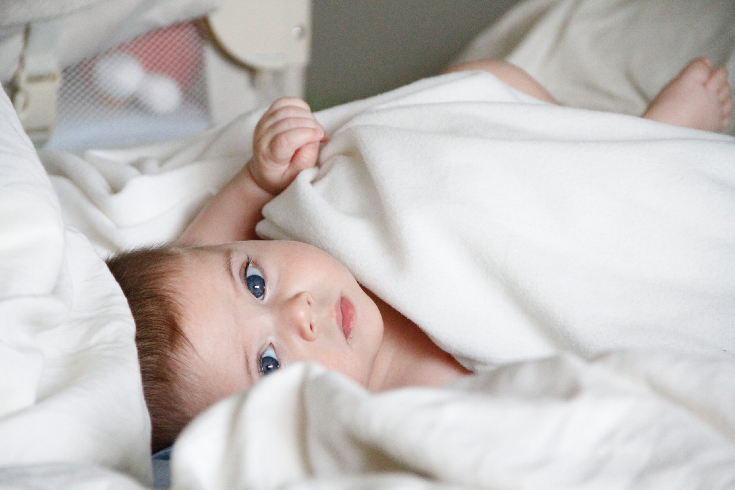 Baby lying on a bed with a white blanket.