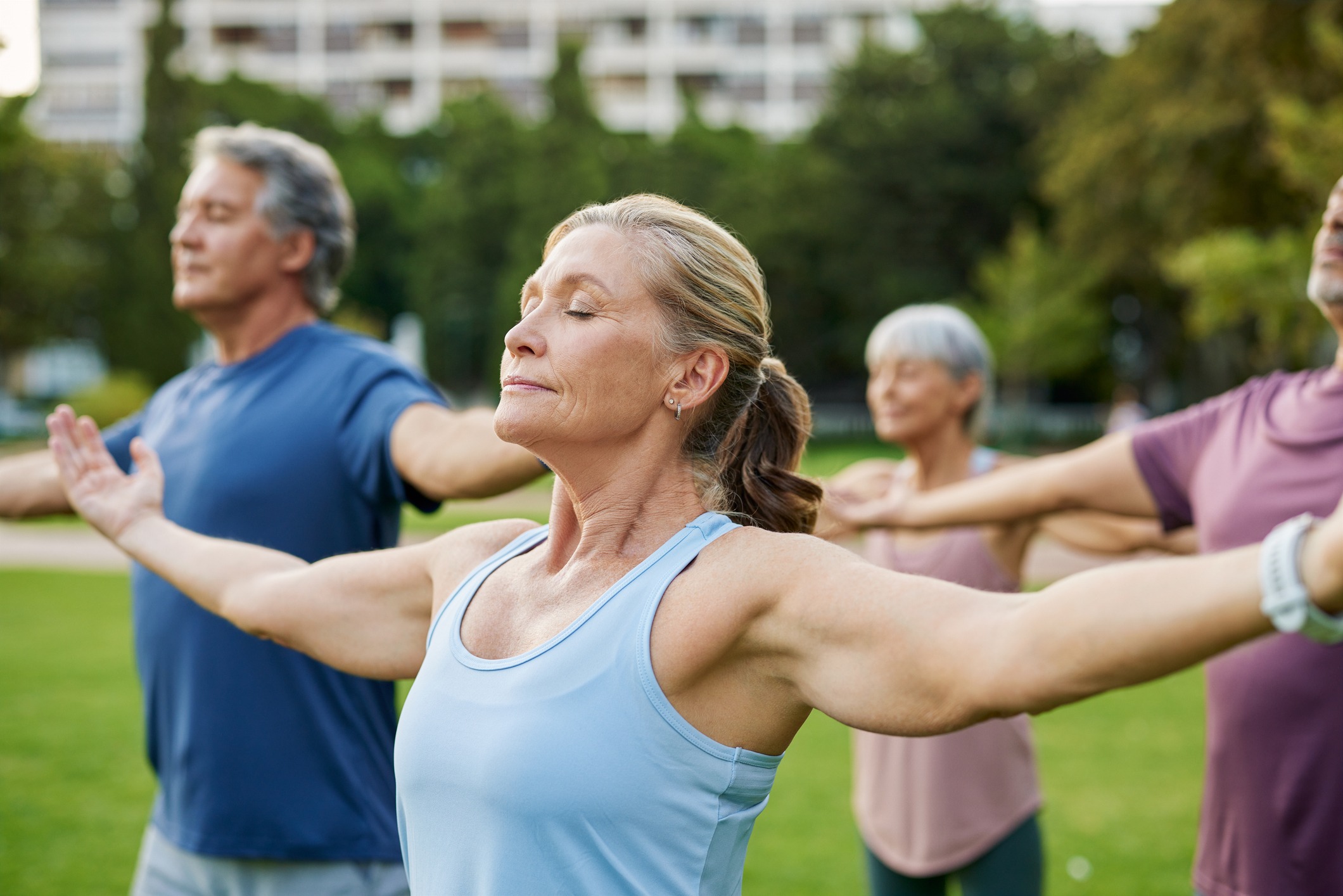 Older woman meditating in outdoor yoga session with closed eyes.