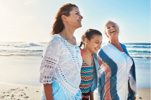 Three women sitting on a couch, smiling and talking.