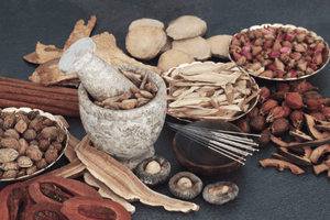 A collection of herbs and spices with a stone mortar and pestle.
