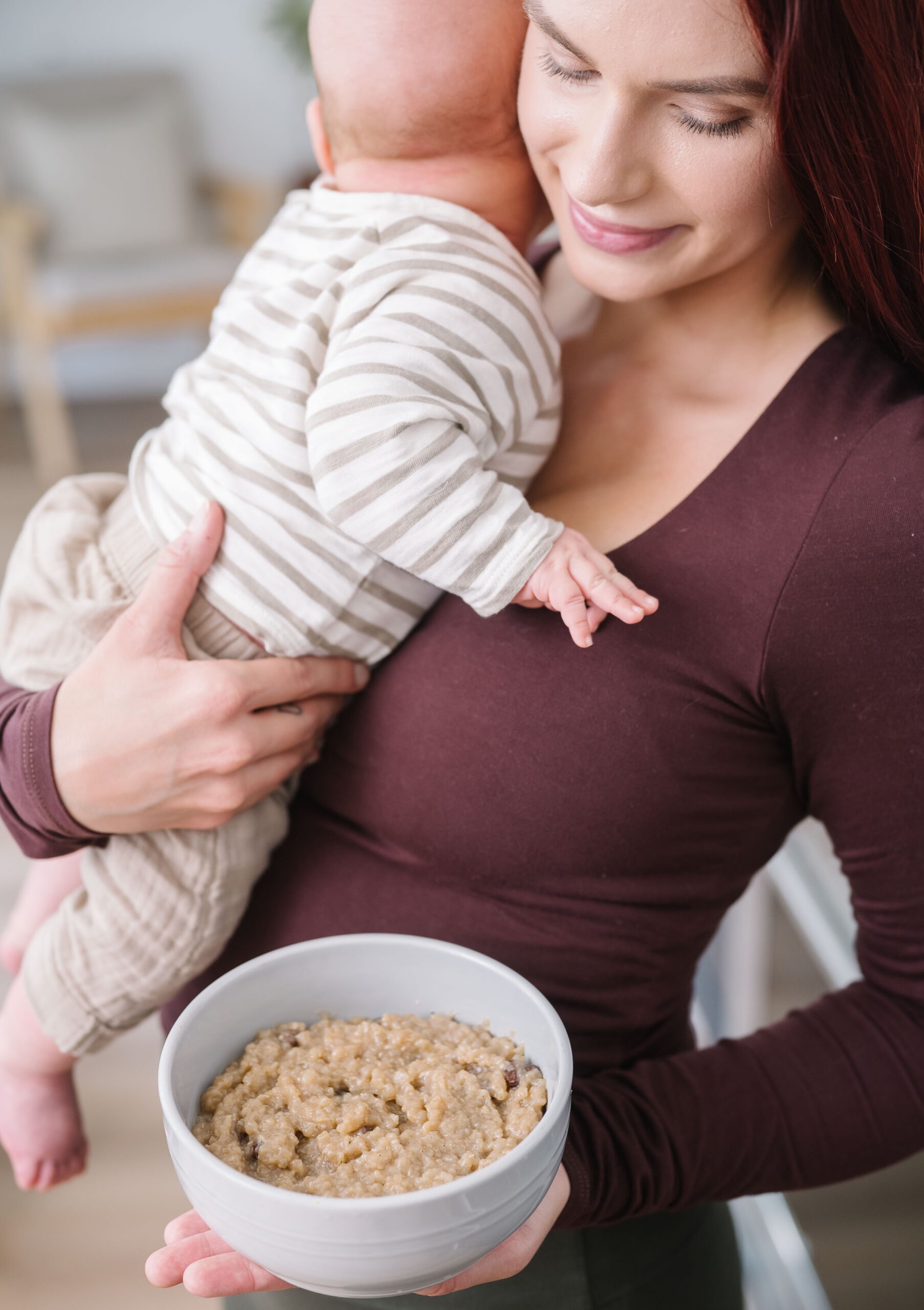 Mother holding her baby and a bowl of nourishing postpartum food